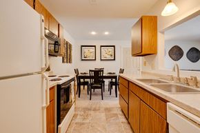 West Des Moines apartment for rent - Kitchen and dining area in a Regency Woods model apartment featuring countertops, appliances, and dining seating.
