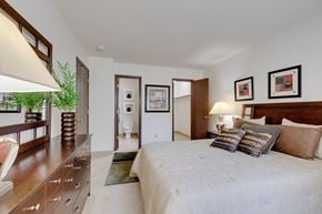 West Des Moines apartment for rent - Regency Woods model unit bedroom featuring a large bed and a wooden dresser.