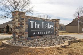 Kansas City apartment for rent - The Lakes apartment complex entrance sign with a stone-brick backing and the clubhouse visible in the background.