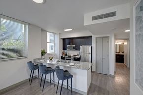 Miami apartment for rent - a kitchen with a marble counter top and a bar with four stools