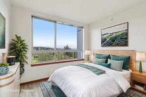 Seattle apartment for rent - A bedroom with a large bed and a view of the outdoors through a large window.