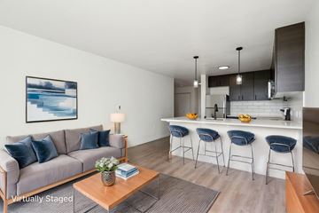 Seattle apartment for rent - A living room with a grey couch and a coffee table with a vase of flowers on it.