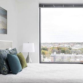 Boston apartment for rent - A bedroom with a large bed and a view of a cityscape through a window.