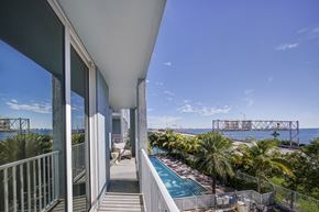 Miami apartment for rent - a balcony with a pool and a view of the water and a bridge