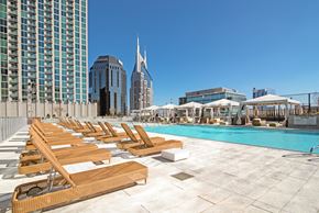 Nashville apartment for rent - A pool with sun loungers in front of a city skyline.