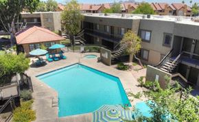 Phoenix apartment for rent - A swimming pool surrounded by a patio area with a table and chairs.