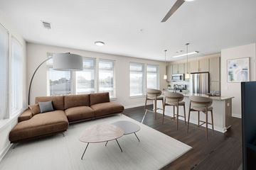 Durham apartment for rent - A modern living room with a brown sofa and a grey floor lamp.