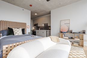 Chicago apartment for rent - A bedroom with a bed, a couch, and a small kitchenette.