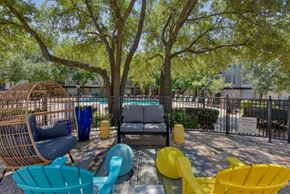 San Antonio apartment for rent - a courtyard with couches and chairs and a pool in the background