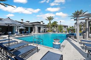Orlando apartment for rent - A pool surrounded by sun loungers and umbrellas.