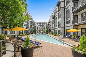 Charlotte apartment for rent - A pool area with sun loungers and umbrellas in front of apartment buildings.