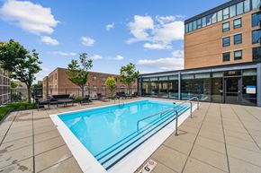 Evanston apartment for rent - A swimming pool in a sunny outdoor area with a building in the background.