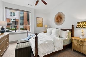 Baltimore apartment for rent - A bedroom with a large bed and a view of a city street outside the window.