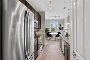 The Woodlands apartment for rent - A modern kitchen with a stainless steel refrigerator and wooden flooring.