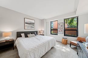 Evanston apartment for rent - A bedroom with a large bed and a window overlooking a cityscape.