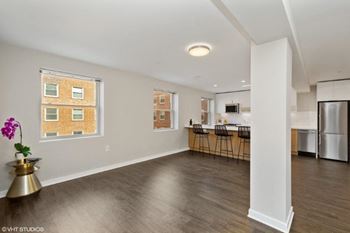 An empty living room with a kitchen in the background