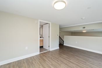 A bedroom with hardwood floors and white walls