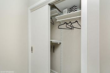 A closet with a white door and a white shelf with glasses on it