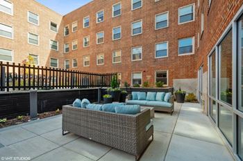 A patio with furniture and a brick building in the background