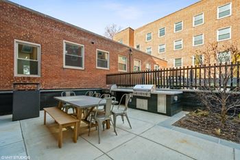 A patio with a table and chairs and a grill