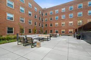 A courtyard with couches and tables in front of a brick building