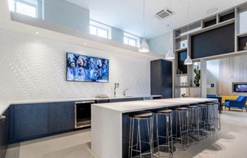 A kitchen with a long island with a white countertop and blue stools