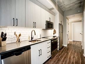 Washington apartment for rent - A kitchen with white cabinets and black appliances at Coda on H Apartments, Washington, DC 20002
