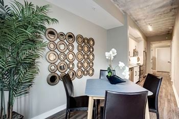 A dining room with a table and chairs and a plant