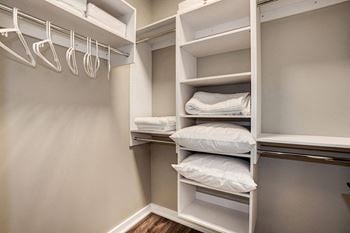 A walk in closet with white shelves and pillows
