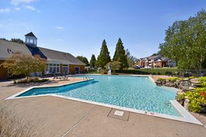 Spotsylvania apartment for rent - A large outdoor swimming pool surrounded by trees and a building.