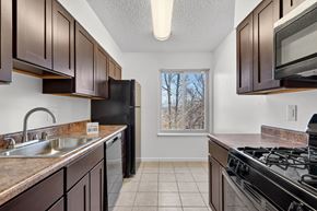 Washington apartment for rent - A kitchen with brown cabinets and black appliances.