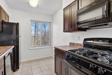 Washington apartment for rent - A kitchen with black appliances and brown cabinets.