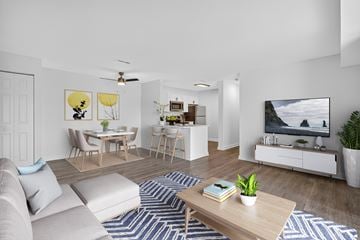 Washington apartment for rent - A living room with a grey sofa, a wooden coffee table, a TV, and a painting on the wall.