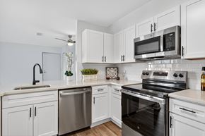 Washington apartment for rent - A modern kitchen with white cabinets and stainless steel appliances.