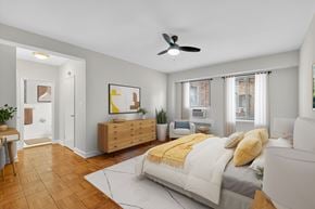 Washington apartment for rent - A bedroom with a bed, a couch, a ceiling fan, and a wooden dresser.