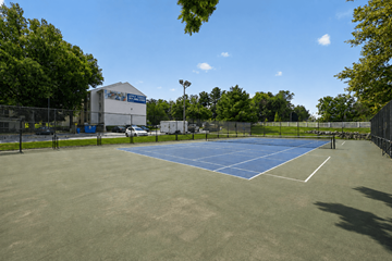 Frederick apartment for rent - A tennis court surrounded by a fence and trees.