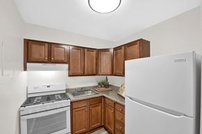 Washington apartment for rent - a kitchen with white appliances and brown cabinets and a refrigerator