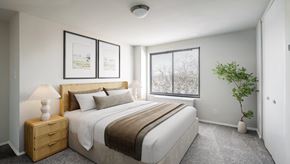 Hyattsville apartment for rent - A bedroom with a large bed, a nightstand, and a plant.