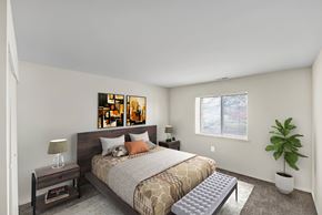 Washington apartment for rent - A bedroom with a bed, nightstand, and a plant.