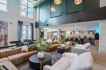 Charlotte apartment for rent - A modern living room with a brown leather couch and a coffee table with a white vase on it.