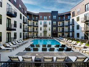 Nashville apartment for rent - A swimming pool surrounded by lounge chairs in front of apartment buildings.