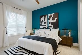 Nashville apartment for rent - A bedroom with a bed, nightstand, and a large abstract painting on the wall at Vintage Edge Nashville Apartments, Nashville, TN