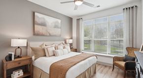 Raleigh apartment for rent - A well-lit bedroom with a large bed, a painting on the wall, and a window with blinds at Vintage Raleigh West Apartments, Raleigh, North Carolina