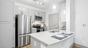 Raleigh apartment for rent - A modern kitchen with a stainless steel refrigerator and white countertops at Vintage Raleigh West Apartments, North Carolina
