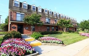 Baltimore apartment for rent - A brick building with a flower bed in front.
