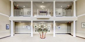 Suitland apartment for rent - the lobby of a large building with a balcony and a table at Windsor Crossing Senior, Suitland Maryland 