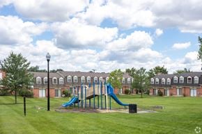Baltimore apartment for rent - A playground with a blue slide in the middle of a grassy area.