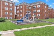 Silver Spring apartment for rent - A playground with a blue slide is in front of a red brick building.