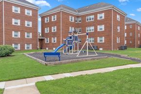 Silver Spring apartment for rent - A playground with a blue slide is in front of a red brick building.