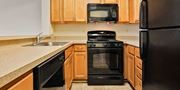 Mount Rainier apartment for rent - A black stove top oven sits in a kitchen with wooden cabinets. at Rainier Manor Apartments, Maryland, 20712